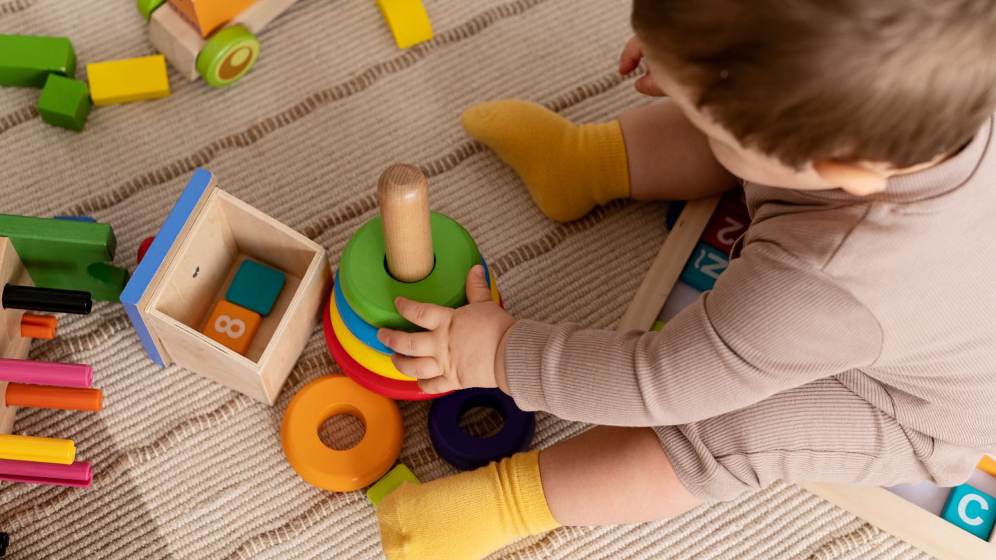 high-angle-kid-playing-with-colorful-toys